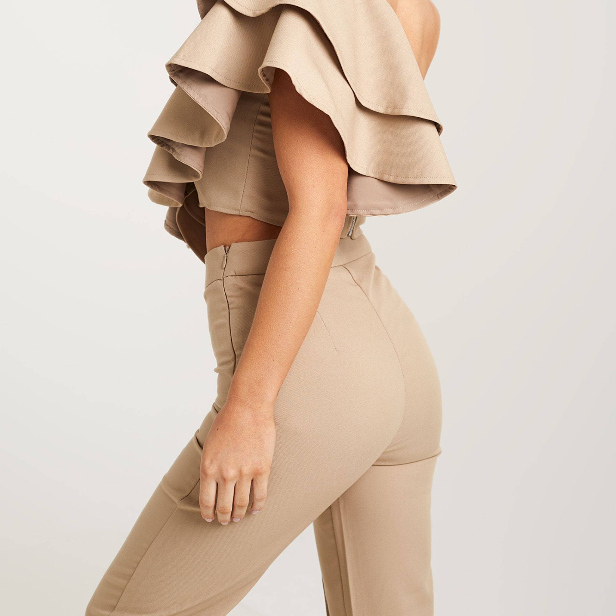 A pair of women's high-waisted, wide-leg suit trousers in a soft beige color. The trousers feature a tailored fit and sit comfortably at the waist, accentuating the feminine silhouette. The wide legs gracefully flow down, creating a sophisticated and elegant look. The neutral beige tone adds a timeless touch to the ensemble, making these trousers versatile for various occasions. 